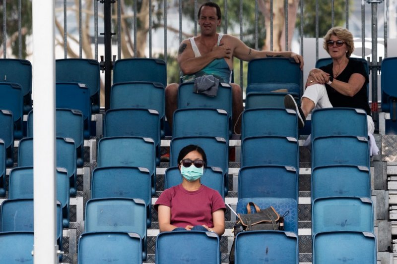 Arsip foto - Seorang wanita mengenakan masker menyaksikan latihan di Melbourne jelang turnamen tenis Australian Open 15 Januari 2020 (AFP/ASANKA BRENDON RATNAYAKE)

