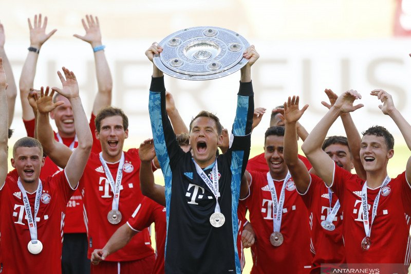 Kiper Bayern Munich Manuel Neuer (tengah) mengangkat trofi saat para pemain Bayern Munich merayakan keberhasilan menjuarai Liga Jerman setelah bermain melawan Wolfsburg di Volkswagen Arena, Wolfsburg, Sabtu (27/6/2020). (ANTARA/AFP/KAI PFAFFENBACH)