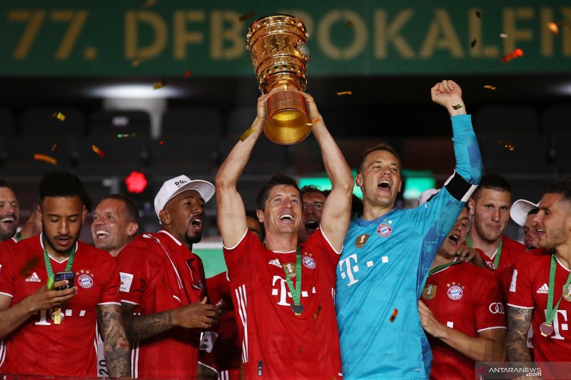 Penyerang Bayern Munich Robert Lewandowski mengangkat trofi Piala Jerman ketika ia danrekan-rekan setimnya merayakan keberhasilan menjuarai ajang itu setelah mengalahkan Bayer Leverkusen pada final yang berlangsung di Olympiastadion, Berlin, Sabtu (4/7/20