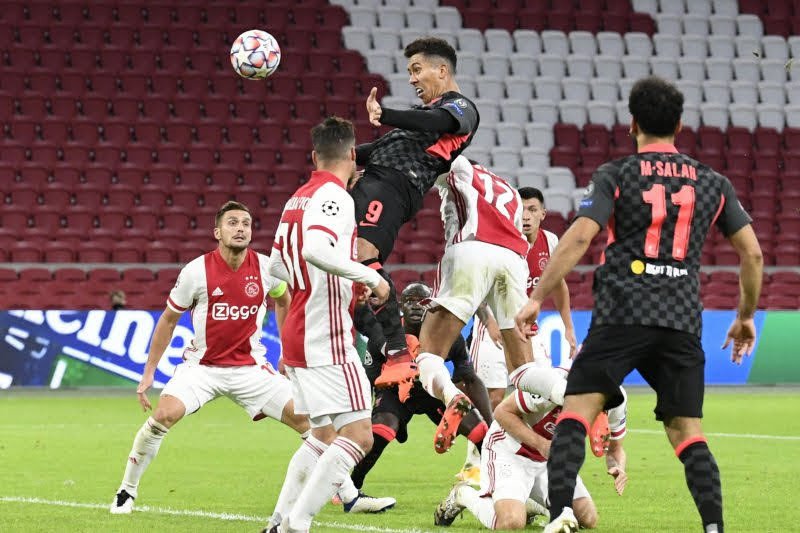 Aksi penyerang Liverpool Roberto Firmino saat melakukan sundulan di tengah kawalan pemain Ajax saat keduanya bertemu di laga perdana Liga Champions Grup D di Johan Cruijff Arena, Rabu (21/10/2020). Liverpool menang tipis 1-0 berkat gol bunuh diri Nicolas 