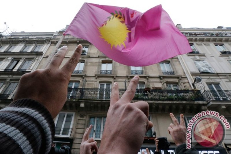 Anggota komunitas Kurdi meneriakkan yel-yel saat mereka berkumpul di depan pintu masuk Pusat Informasi Kurdistan di Paris, Perancis, dimana tiga perempuan Kurdi ditemukan ditembak mati, Kamis (10/1). Tiga aktivis perempuan Kurdi, termasuk salah satu pendi