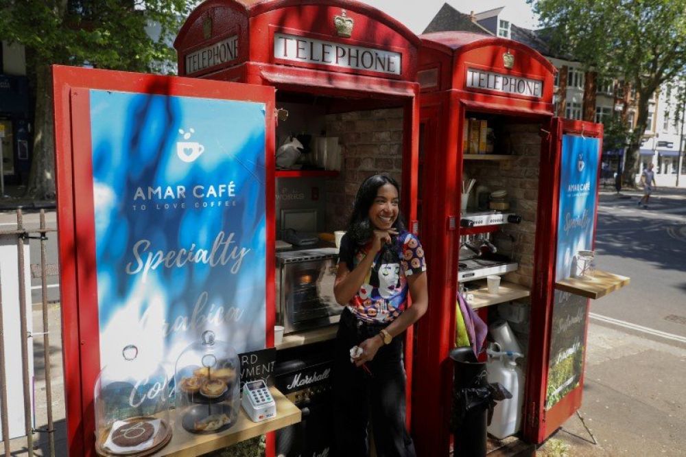 Loreinis Mejia Hernandez dari Colombia tersenyum di depan boks telepon umum Inggris yang dijadikan warung kopi di Chiswick, London, Inggris, 2 Juni 2020. (REUTERS/Kevin Coombs)