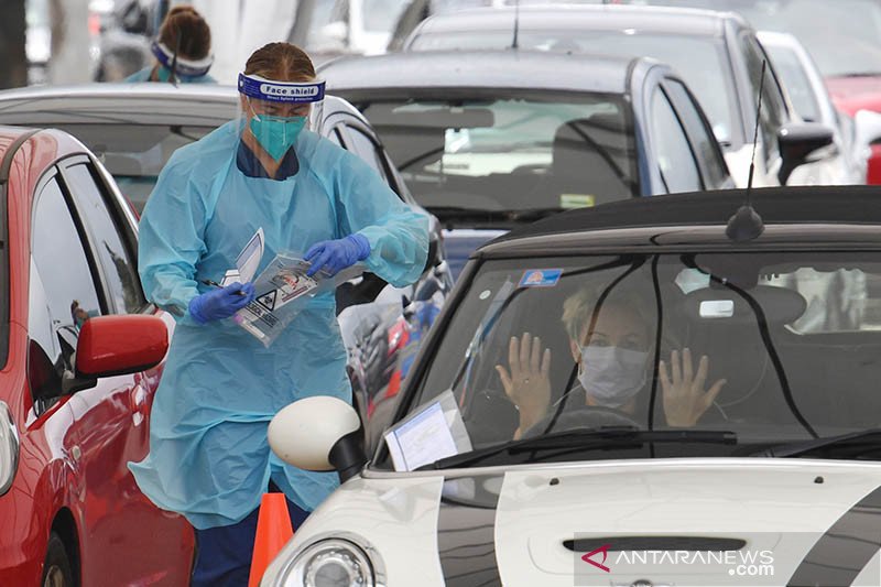 Seorang petugas medis melayani warga yang antre dalam kendaraan mereka untuk tes COVID-19 dengan cara lantatur di klinik Rumah Sakit St.Vincent di kawasan pantai Bondi, Sydney, Minggu (20/12/2020). Pantai utara Sydney diisolasi karena klaster corona terus