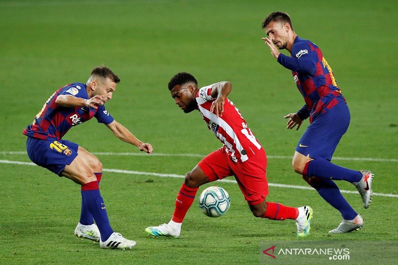 Sayap Atletico Madrid Thomas Lemar (tengah) berusaha melewati hadangan bek Barcelona Jordi Alba (kiri) dan Clement Lenglet dalam laga lanjutan Liga Spanyol tanpa penonton di tengah pandemi COVID-19 di Stadion Camp Nou, Barcelona, Spanyol, Selasa (30/6/202