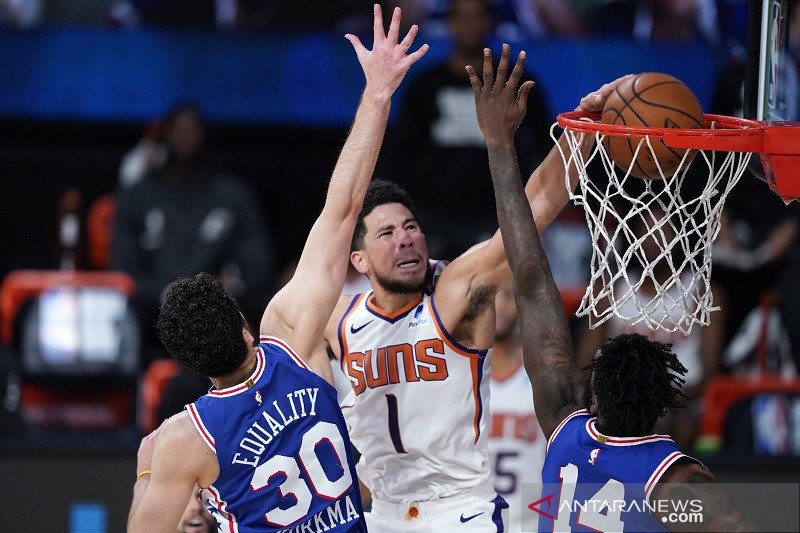 Bintang Phoenix Suns Devin Booker (tengah) menghempaskan dunk di hadapan kawalan duo pemain Philadelphia 76ers Furkan Korkmaz (kiri) dan Norvel Pelle dalam laga lanjutan NBA di VISA Athletic Center, Florida, Amerika Serikat, Selasa (11/8/2020) waktu setem