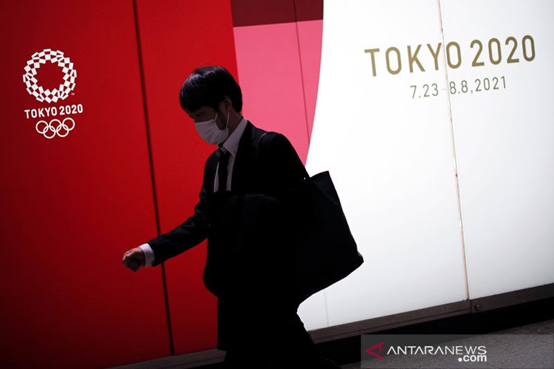 Seorang pria yang mengenakan masker pelindung berjalan melewati iklan Olimpiade Tokyo 2020 yang telah ditunda hingga 2021 karena wabah penyakit coronavirus (COVID-19), di Tokyo, Jepang, 22 Januari 2021. ANTARA/REUTERS / Issei Kato/pri. (REUTERS/ISSEI KATO