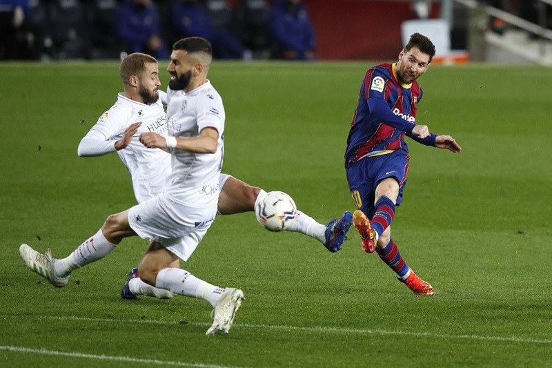 Megabintang Barcelona Lionel Messi (kanan) melepaskan tembakan untuk mencetak gol keempat timnya ke gawang Huesca dalam lanjutan Liga Spanyol di Stadion Camp Nou, Barcelona, Spanyol, Senin (15/3/2021) waktu setempat (ANTARA/REUTERS/Albert Gea)
