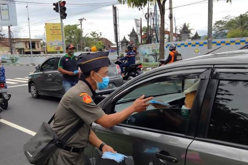 Seorang anggota GP Ansor Kabupaten Magelang membagikan masker kepada pengguna jalan raya setempat, Sabtu (2/1/2021). (ANTARA/HO-GP Ansor Kabupaten Magelang)

