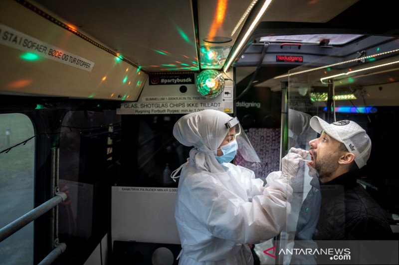 Petugas kesehatan mengambil sampel usap dari seseorang di Partybus, di mana orang-orang dapat mendengarkan musik sambil uji usap, di Ishoej, Denmark, Selasa (23/2/2021). Ritzau Scanpix/Mads Claus Rasmussen via REUTERS/WSJ/djo (via REUTERS/RITZAU SCANPIX)