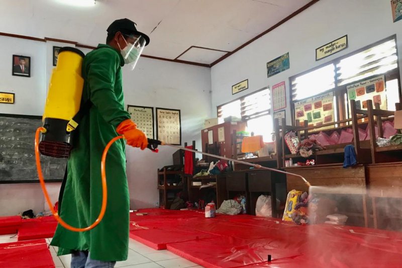 Petugas melakukan penyemprotan disinfektan di lokasi pengungsian warga terdampak tanah longsor di Gedung SD Negeri 3 Ngetos, Kabupaten Nganjuk, Jawa Timur, Selasa (16/02/2021). (ANTARA/Fiqih Arfani)