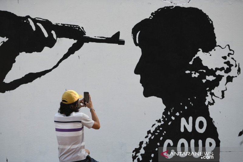 Seorang warga memotret grafiti buatan seniman Thailand Mue Bon, yang menentang kudeta militer di Myanmar, di sebuah jalan di Bangkok, Thailand, Sabtu (6/2/2021). REUTERS/Chalinee Thirasupa/WSJ/djo (REUTERS/CHALINEE THIRASUPA)
