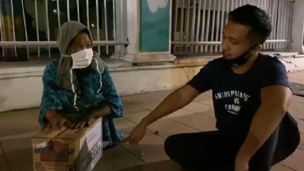 Seorang pria memberi bingkisan kepada warga. (FOTO: Tangkapan layar Instagram @tomliwafa)