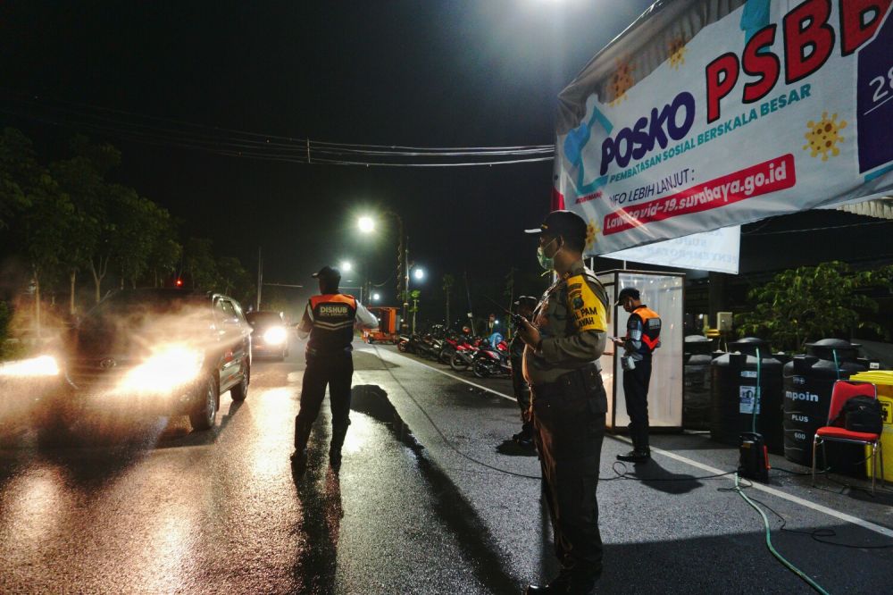 Petugas memberikan semprotan disinfektan bagi pengendara roda 4 di perbatasan wilayah masuk Surabaya. ( foto : Zul/hmp)