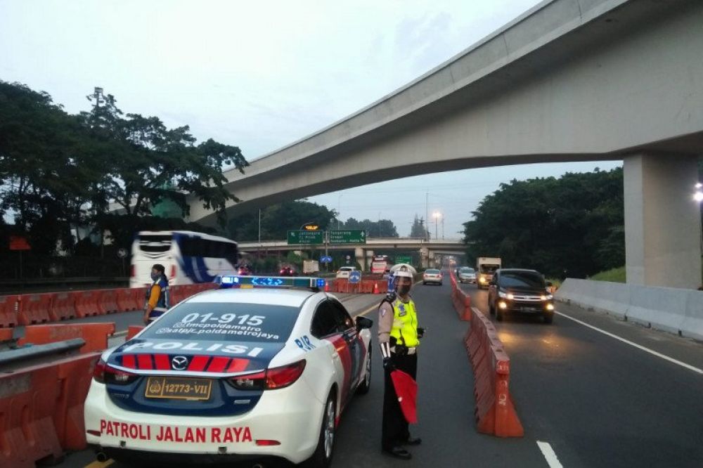 Petugas kepolisian mengatur lalu lintas di sekitar kawasan Halim yang mengarah ke lintasan Tol Dalam Kota Jakarta, Selasa (9/6/2020). Petugas menerapkan rekayasa lawan arah dalam rangka mengurangi potensi kepadatan kendaraan di sekitar Simpang Susun Cawan