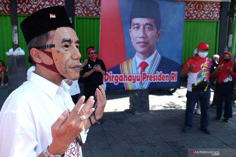 Warga memakai topeng bergambar Presiden Joko Widodo berdoa bersama untuk merayakan hari kelahiran ke-59 Jokowi, di Solo, Jawa Tengah, Minggu (21/6/2020). ANTARA FOTO/Maulana Surya