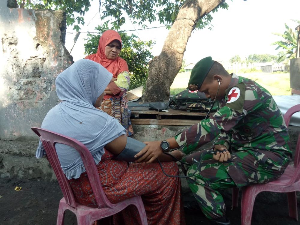 TNI DAN RAKYAT: Salah satu anggota Yon Armed 9 memeriksa sslah satu warga. HMP/cho.