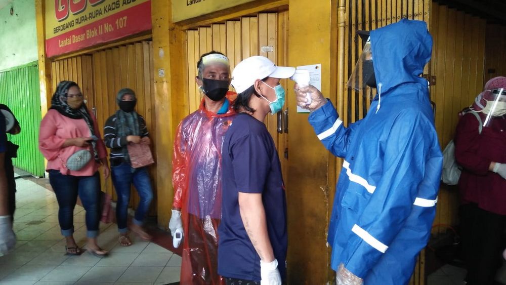 Pedagang pasar Kapasan Surabaya diperiksa suhu tubuhnya sebelum mulai kembali berjualan. | HMP/DOK