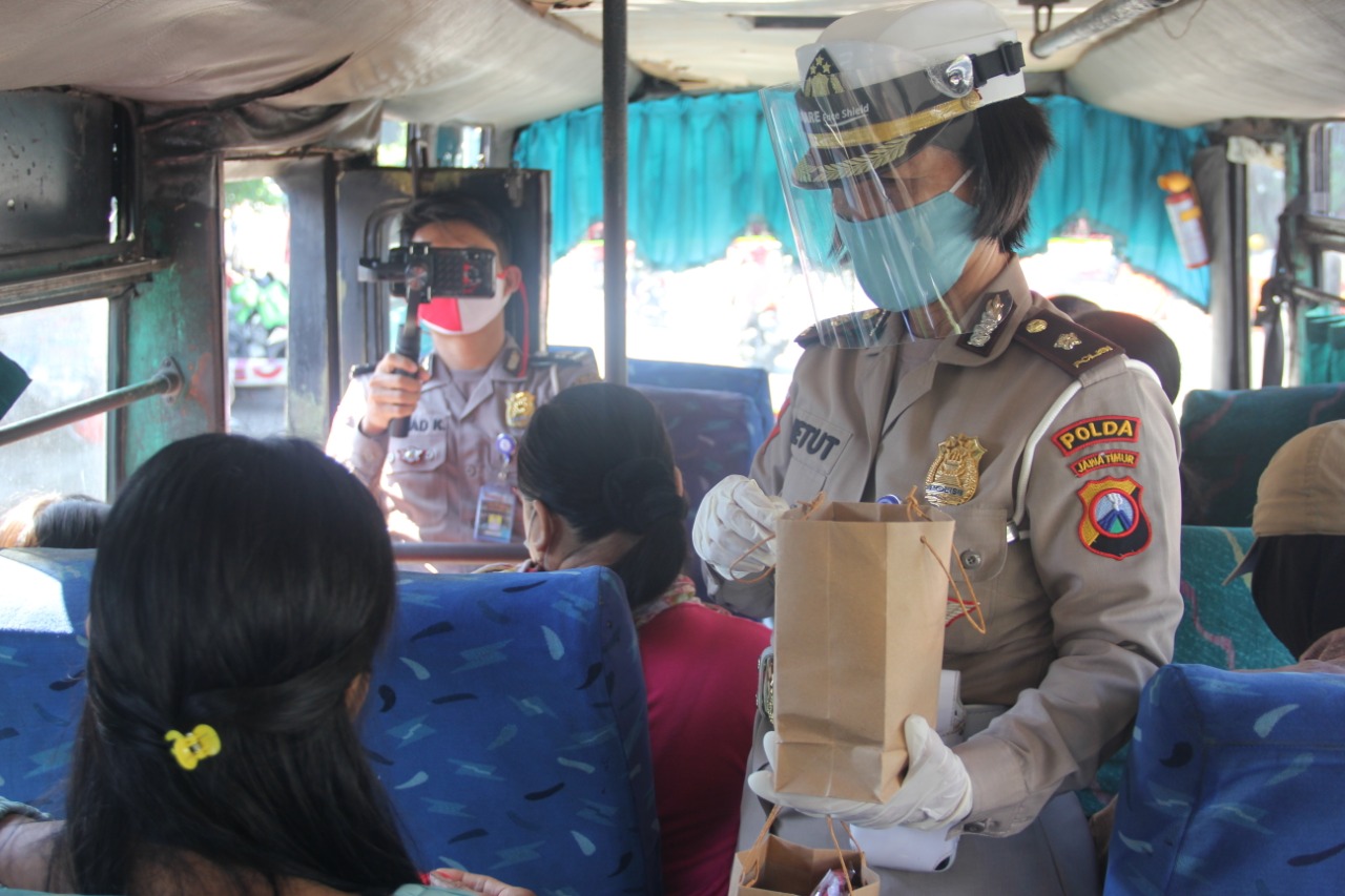 Anggota Subdit Kamsel Ditlantas Polda Jatim ketika membagikan paket masker, hand sanitizer, sarung tangan, kepada penumpang angkutan umum di Terminal Joyoboyo, Surabaya, Senin (13/7/2020).