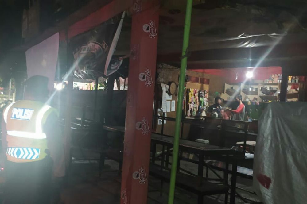 Polsek Tenggilis membubarkan Warkop TT di Jalan Raya Tenggilis karena melanggar jam malam PSBB II Surabaya.