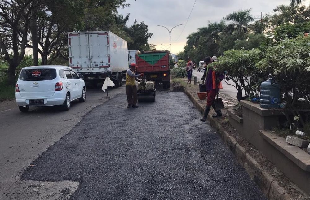 Sejumlah pekerja memperbaiki jalan rusak di Raya Deket, Lamongan, Kamis (4/6).