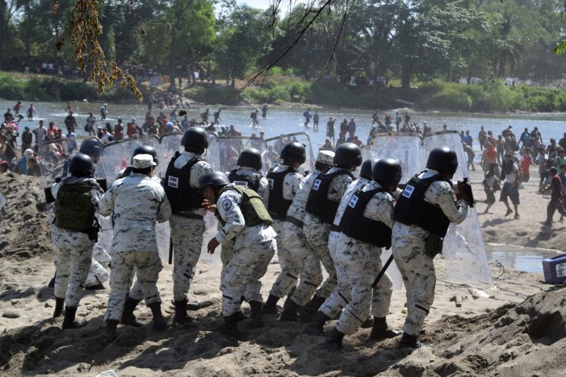 Anggota Garda Nasional Meksiko memegang tameng untuk memblokir imigran, bagian dari kelompok yang menuju Amerika Serikat, dekat perbatasan Guatemala-Meksiko, di Ciudad Hidalgo, Meksiko, Senin (20/1/2020). (REUTERS/JOSE TORRES)
