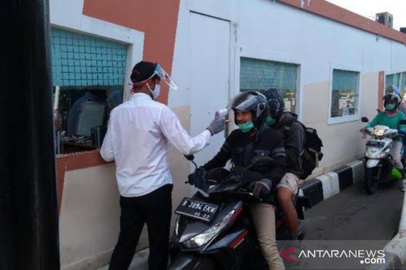 Petugas di pintu masuk Taman Mini Indonesia Indah (TMII) Jakarta Timur mengecek suhu tubuh wisatawan yang datang mengendarai sepeda motor, Minggu (3/1/2021). (ANTARA/HO-Humas TMII).

