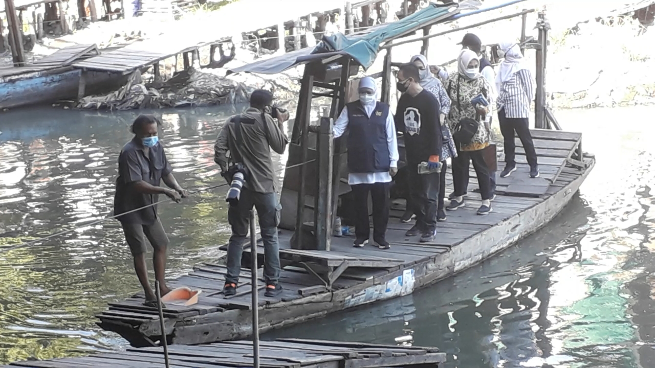 Gubernur Jawa Timur Khofifah Indar Parawansa menaiki perahu rakit penyebrangan di bawah tol Dupak, untuk menyerahkan Bantuan Sosial (Bansos), bagi warga Morokrembangan, Surabaya, Jumat (23/7/2021). 