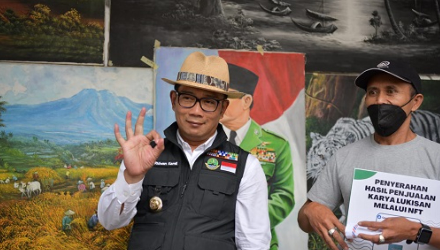  Gubernur Jawa Barat Ridwan Kamil menyerahkan uang hasil penjualan lukisan milik penjual lukisan di Jl. Braga, Kota Bandung, yang ia bantu penjualannya lewat NFT (Non-Fungible Tokens) Opensea.