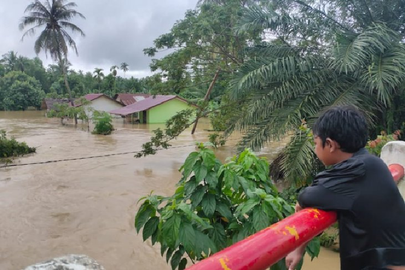 Seorag warga menyaksikan rumah yang terendam banjir di Gampong Tanjong Haji Muda, Matangkuli, Aceh Utara, Sabtu (5/12/2020) ANTARA/HO

