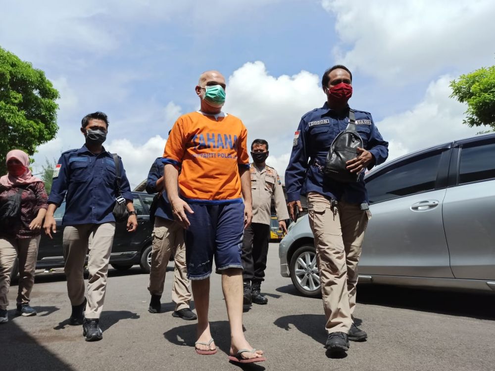 Salah seorang tersangka investasi bodong memilis saat diserahkan ke Kejati Jatim. ( foto : ris/hmp)