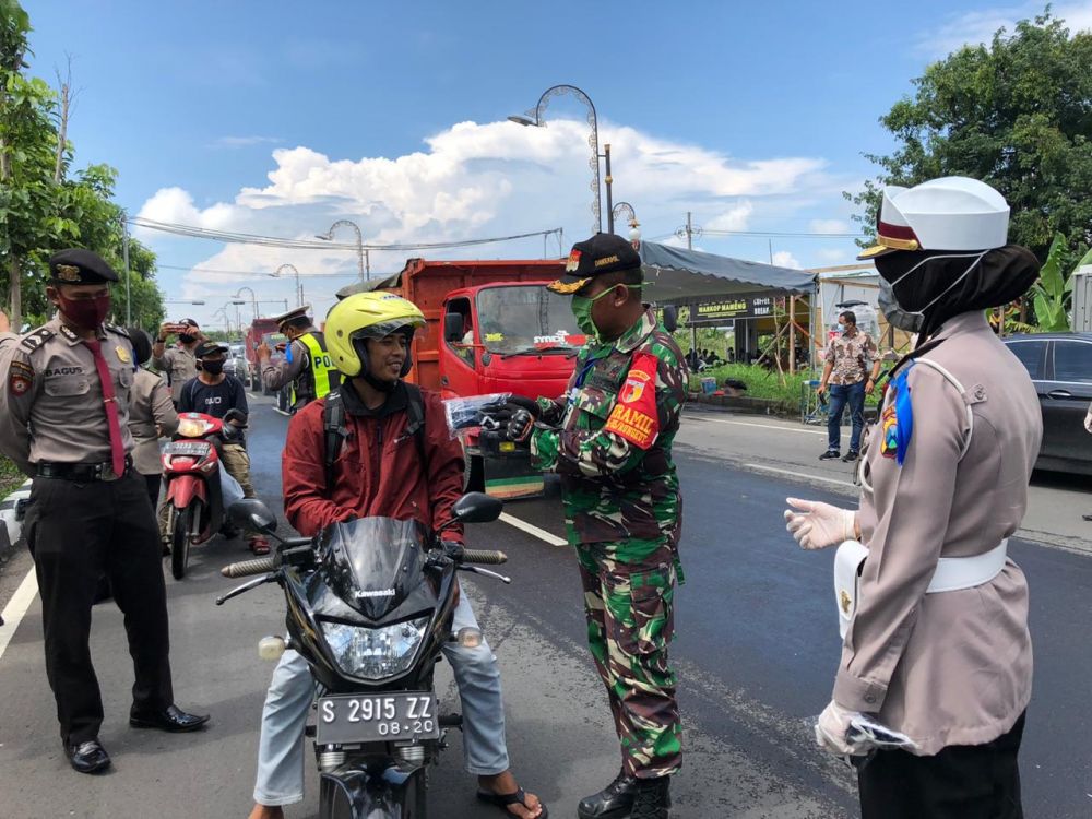 Anggota Ditlantas Polda Jatim dan melibatkan TNI bagi masker di jalan Jemursari Surabaya. (foto:ris/hmp)