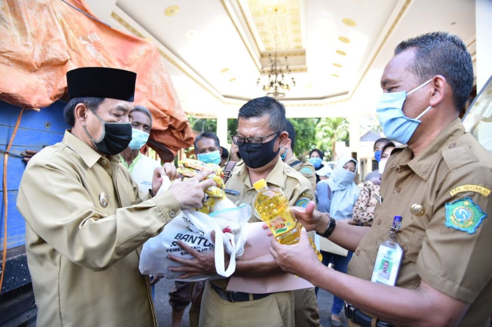Plt. Bupati Nur Ahmad Syaifuddin  saat memeriksa isi paket sembako. ( foto: bil/hmp)