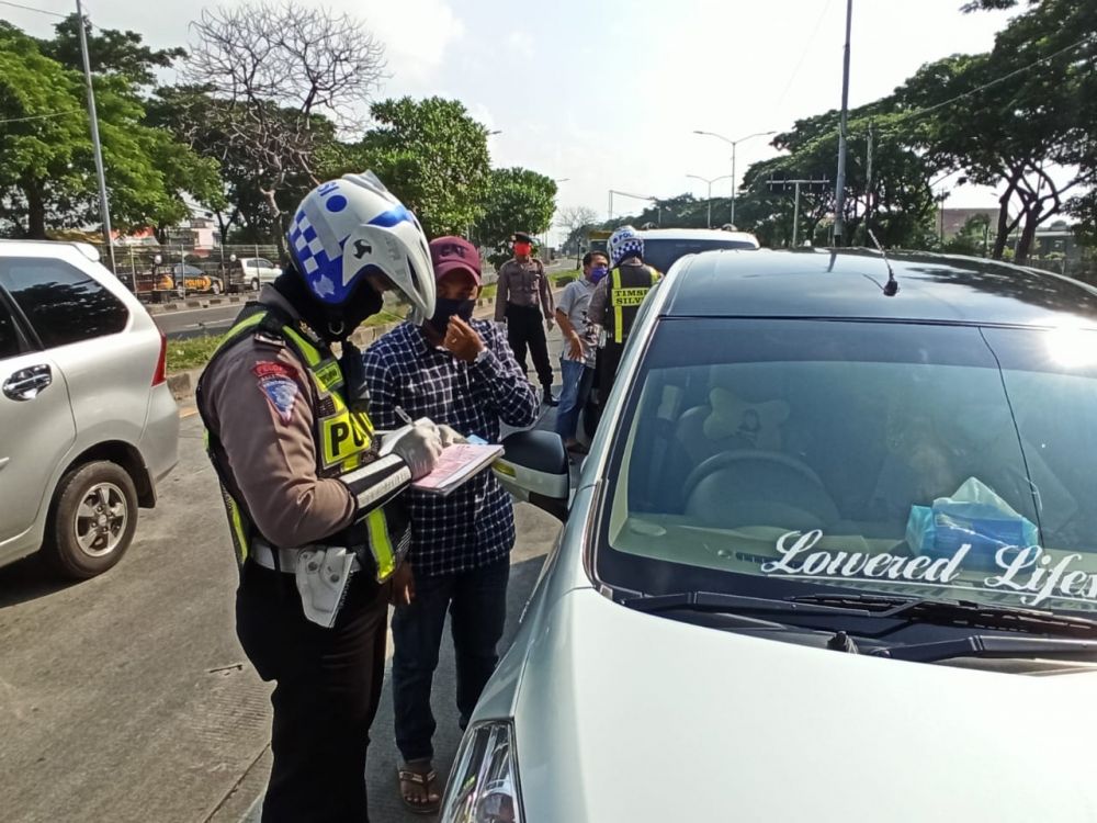 Petugas saat memberikan surat tilang kepada pengendara di pintu keluar jembatan suramadu. ( foto : ris/hmp)  