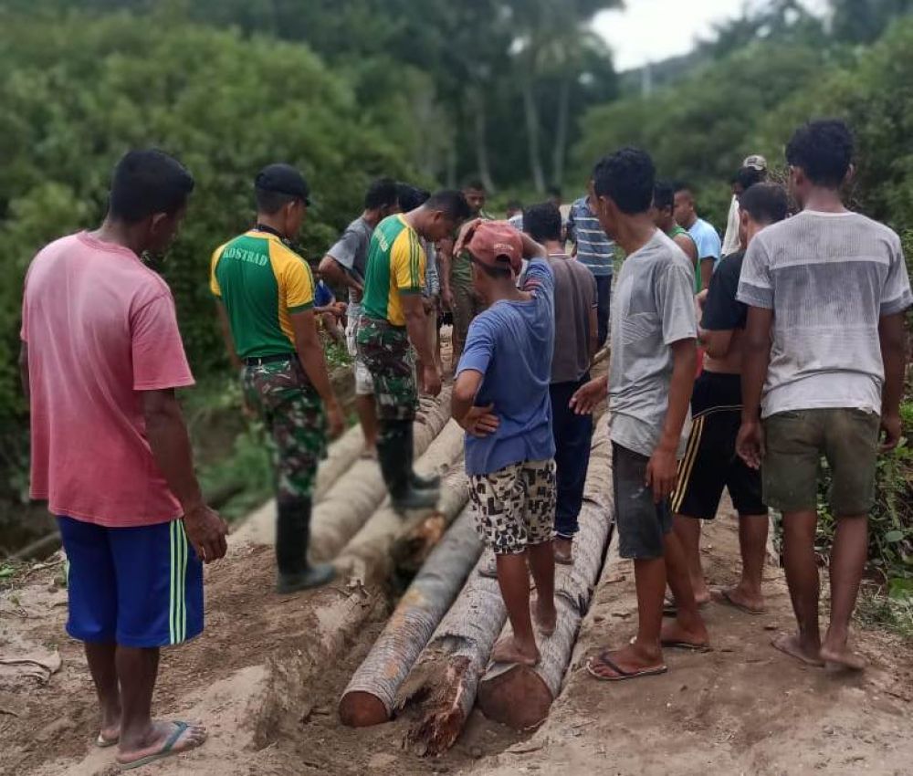 Satgas Yonarmed 9 dan warga bahu-membahu memperbaiki jembatan. HMP/Cho