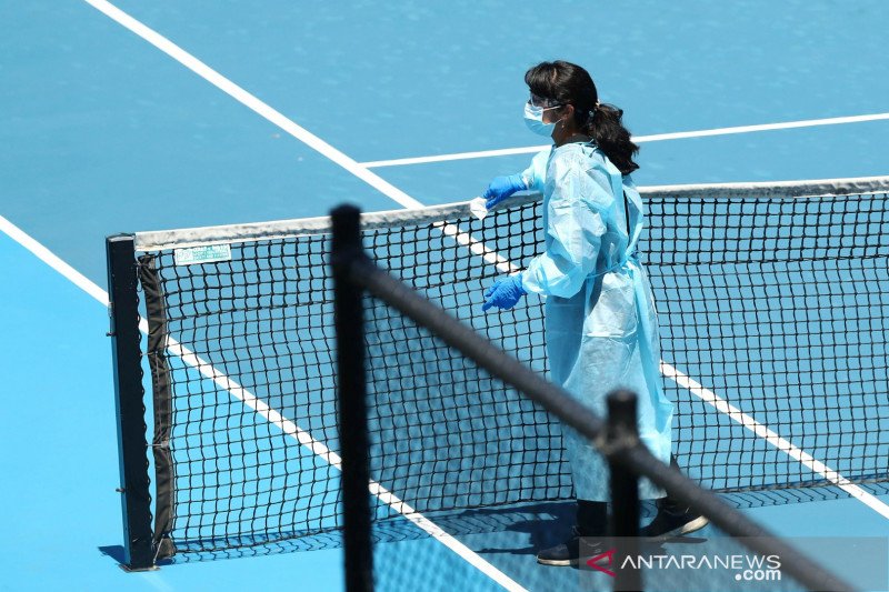 Ilustrasi: Seorang anggota staf memakai alat pelindung diri (APD) membersihkan lapangan di Melbourne Park di antara sesi latihan untuk pemain tenis yang sedang melakukan karantina wajib menjelang turnamen tenis Australia Open di Melbourne, Australia, Kami
