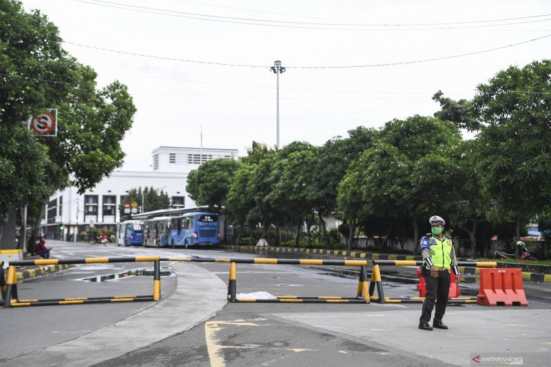 Polisi berjaga di depan Jalan Pintu Besar Utara yang ditutup di kawasan Kota Tua, Jakarta, Selasa (12/1/2021). Pemerintah Kota Administrasi Jakarta Barat menutup sejumlah ruas jalan menuju kawasan wisata Kota Tua selama penerapan Pemberlakuan Pembatasan K