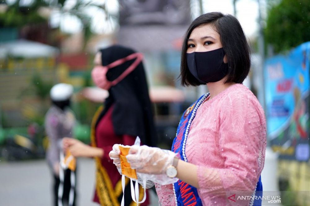 Seorang Polisi Wanita (Polwan) yang mengenakan kebaya membagikan masker kepada pengguna jalan di Kota Gorontalo, Gorontalo, Rabu (22/4/2020). ANTARA FOTO/Adiwinata Solihin/aww. (ANTARAFOTO/Adiwinata Solihin)