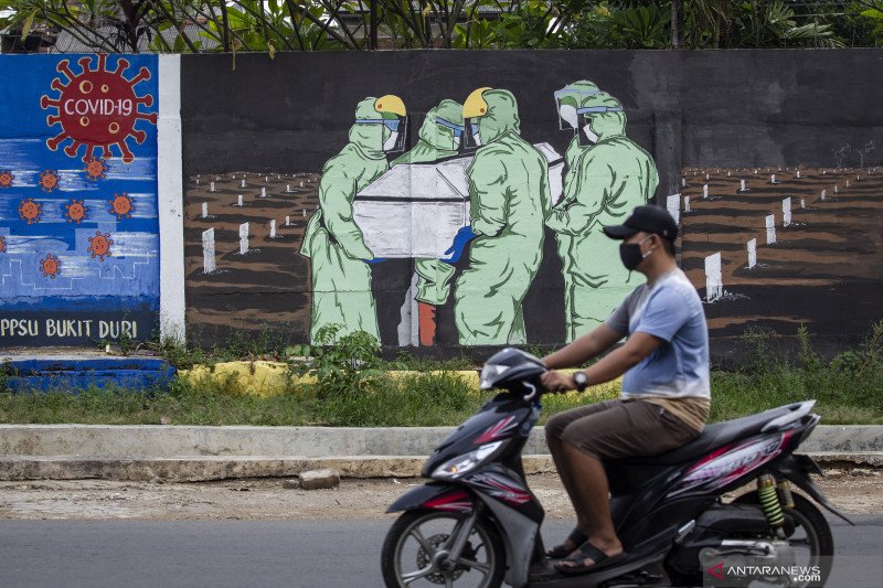 Pengendara motor melintas di depan mural tentang pandemi COVID-19 di Bukit Duri, Jakarta, Minggu (18/10/2020). ANTARA FOTO/Dhemas Reviyanto/pras.