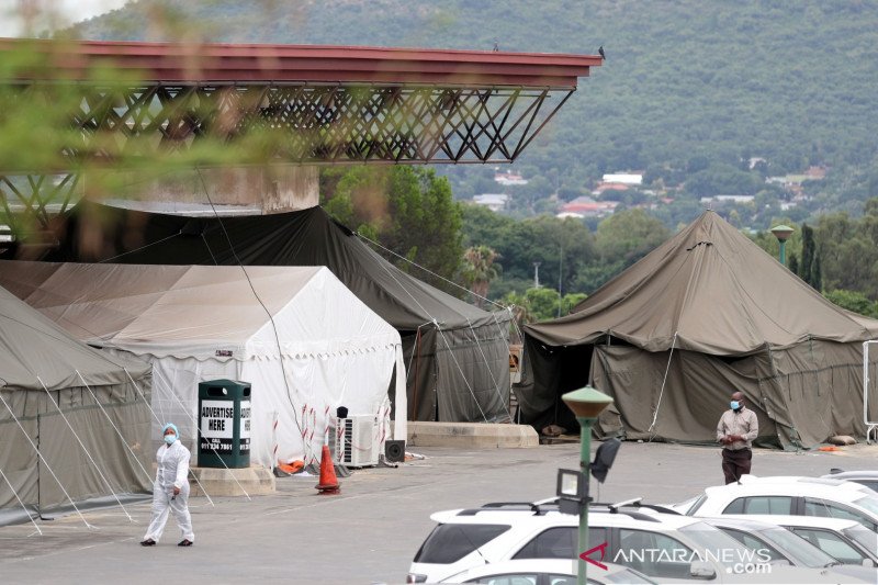 Petugas kesehatan berjalan melewati sejumlah tenda yang dipasang di lapangan parkir Rumah Sakit Akademi Steve Biko, ditengah penguncian nasional akibat wabah penyakit virus corona (COVID-19), di Pretoria, Afrika Selatan, Senin (11/1/2021). ANTARA FOTO/REU