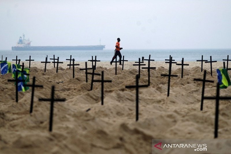 Seorang pria berlari di Rio de Janeiro, Brazil, Kamis (11/6/2020), melewati ratusan makam yang digali oleh aktivis LSM Rio de Paz di pantai Copacabana untuk menyimbolkan banyaknya warga yang meninggal dunia akibat penyakit virus corona (COVID-19). (REUTER