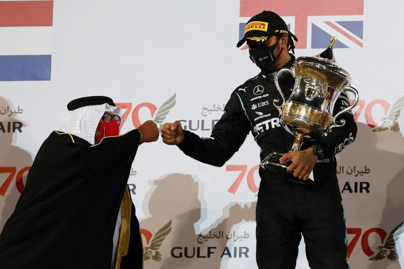 Pebalap tim Mercedes Lewis Hamilton menyalami Pangeran Khalid Bin Sultan Al Faisal, Presiden Saudi Automobile and Motorcycle Federation, setelah menerima trofi juara Grand Prix Bahrain di Sirkuit Internasional Bahrain. (29/11/2020) (Pool via Reuters/Hamad