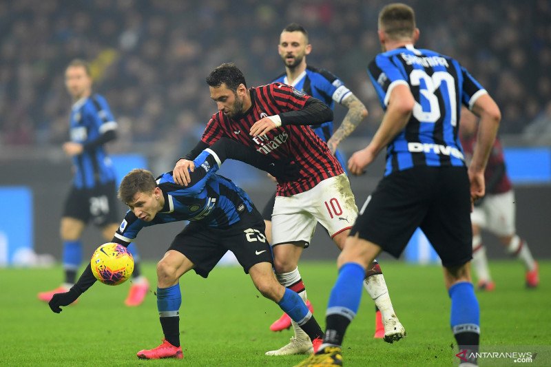 Pesepak bola Inter Milan Nicolo Barella (kiri) bererbut bola dengan pesepak bola AC Milan Hakan Calhanoglu (tengah) dalam laga pekan ke-23 Liga Italia, di Stadion San Siro, Milan, Italia, Minggu (9/2/2020). ANTARA FOTO/Reuters-Daniele Mascolo/hp.

