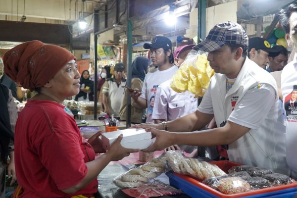 Sekretaris TKD Jatim, Indra Nur Fauzi saat bagikan nasi kotak ke pedagang Pasar Tambakrejo.
