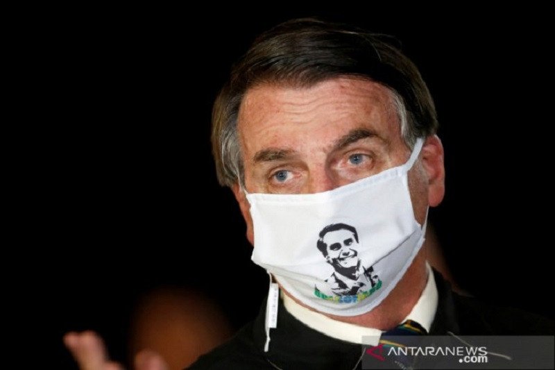 Presiden Brazil Jair Bolsonaro berbicara dengan wartawan sambil memakai masker saat ia tiba di Alvorada Palace di Brasilia, Brazil, Jumat (22/5/2020), di tengah penyebaran penyakit virus corona (COVID-19). (ANTARA/REUTERS/ADRIANO MACHADO/TM)

