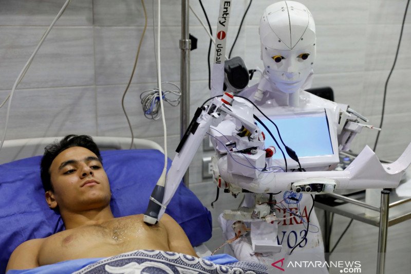 Seorang sukarelawan di Tanta, Mesir, Rabu (18/11/2020), diperiksa oleh Cira 3, robot yang dikendalikan dari jarak jauh untuk melakukan tes terhadap terduga pasien dengan penyakit virus corona (COVID-19) untuk membatasi paparan manusia terhadap virus, di t