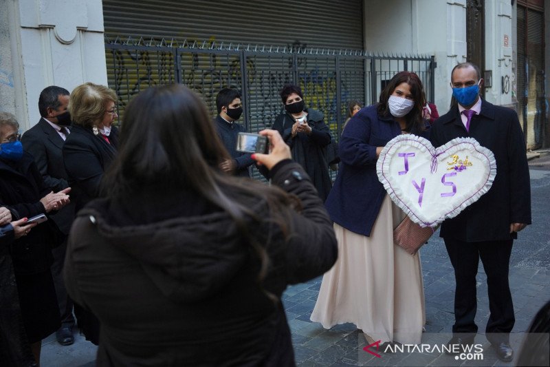 Pasangan baru menikah Sofia Antunez (ki) dan Jonathan Malacria berfoto bersama sambil memakai masker pelindung setelah menikah di kantor pendaftaran status sipil di tengah penyebaran penyakit virus korona (COVID-19) di Montevideo, Uruguay, Jumat (8/5/2020