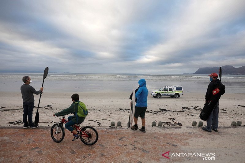 Dokumentasi - Polisi berpatroli saat peselancar dan pengunjung di pantai Muizenberg, Cape Town, Afrika Selatan, Selasa (5/5/2020), melakukan aksi protes untuk menentang aturan karantina (lockdown) nasional, yang hanya membolehkan latihan tapi bukan aktivi